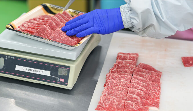 パックに入った肉を秤に乗せて測っている写真